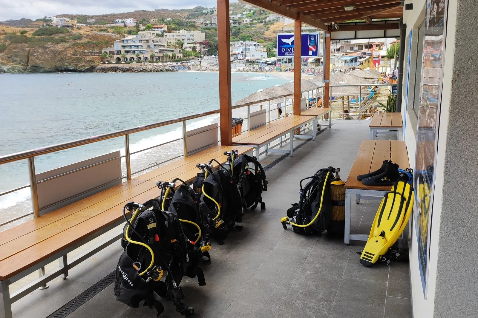 Attrezzatura subacquea allineata sulla terrazza di Divers Club Crete, con vista su una spiaggia e una baia cretesi