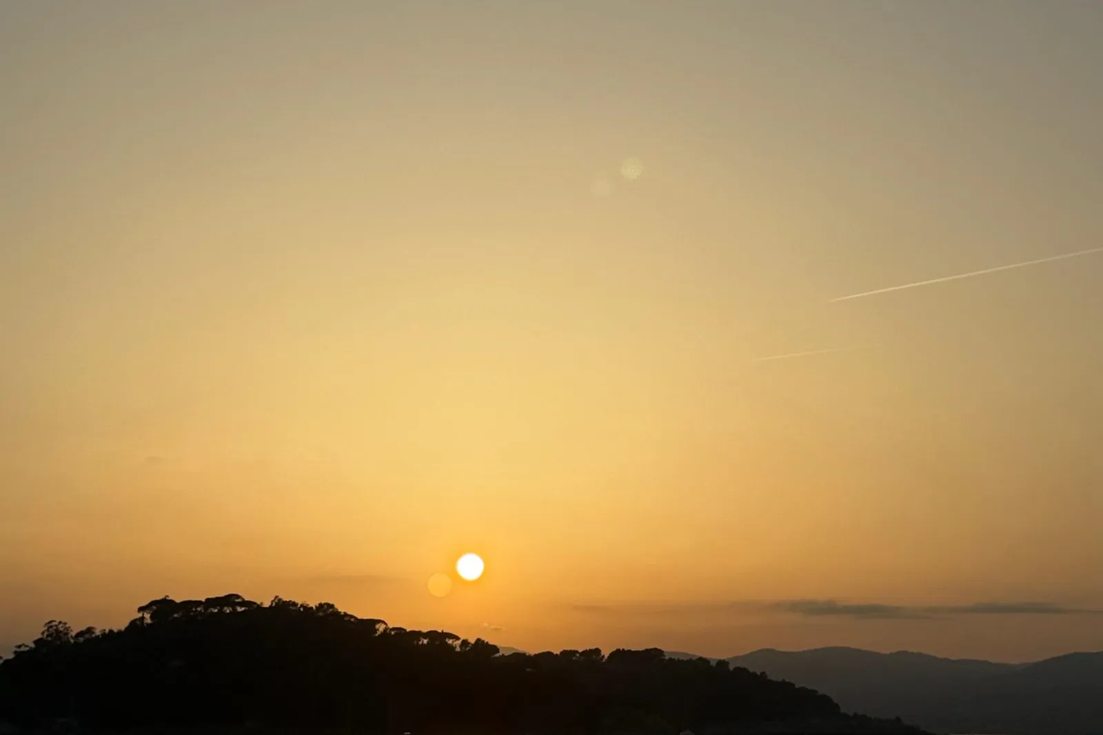 Golden-hour sunset over the calm bay of Saint-Tropez with a small boat silhouetted on the water