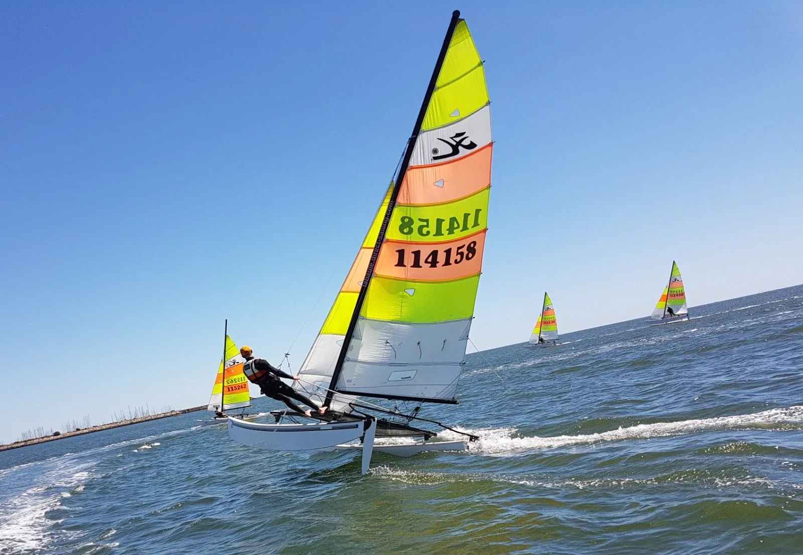 Yagga üssü açıklarında renkli bir Hobie Cat katamaranla yarışan bir denizci
