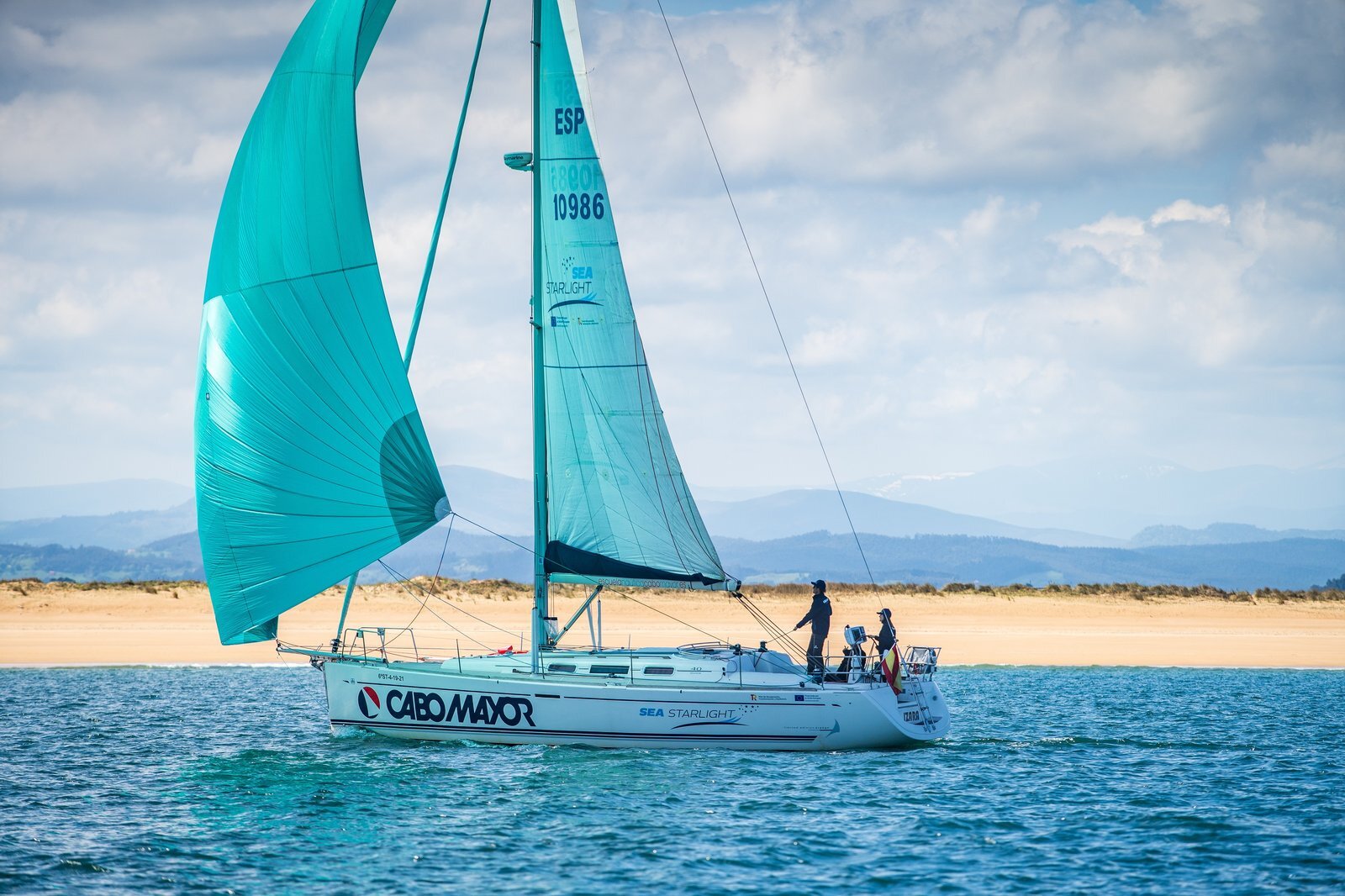 Barca a vela Cabo Mayor con spinnaker turchese nella baia di Santander
