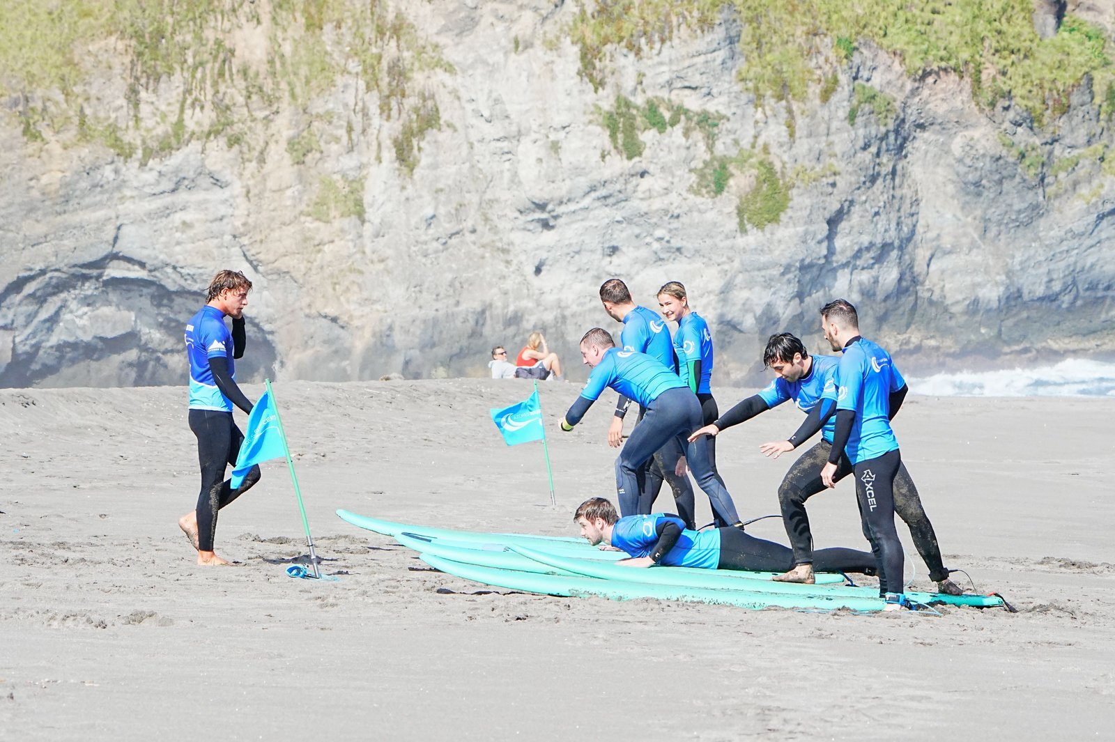 Allievi provano l’alzata in piedi sulla tavola sulla sabbia durante una lezione di Azores Surf Center