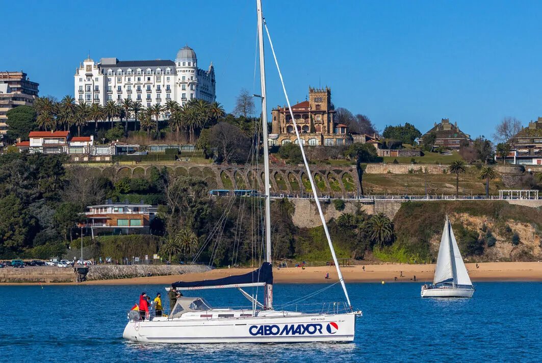 Una barca a vela Cabo Mayor naviga nella baia di Santander, ai piedi dell’hotel simbolo sulla collina