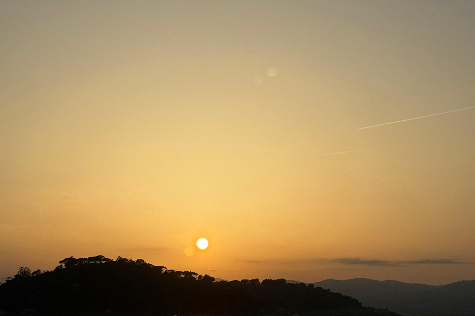 Tramonto dorato sulla baia calma di Saint-Tropez, con una piccola imbarcazione stagliata sull’acqua